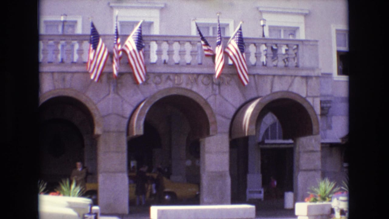 1974 Colorado Springs hotel exterior showing arched stone entryways, balcony flags, planters, and a yellow taxi near people by the entrance.