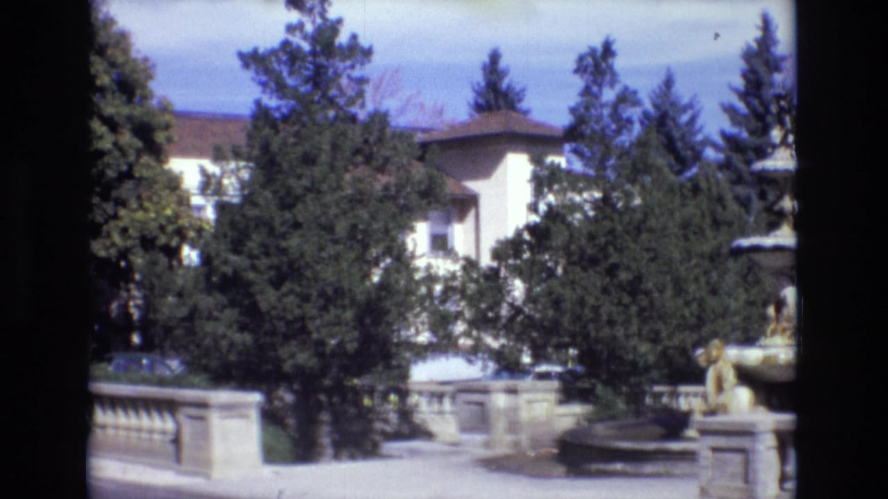 1974 Colorado Springs estate view with the stone fountain at right, trees partly obscuring a pale building, and a low balustrade across the foreground.