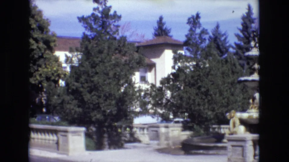 1974 Colorado Springs estate view with the stone fountain at right, trees partly obscuring a pale building, and a low balustrade across the foreground.