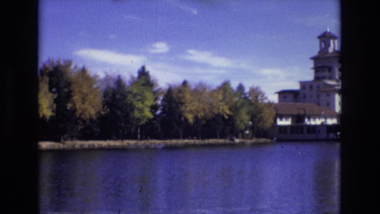 Lake and tree-lined shore with a towered building at the right edge.
