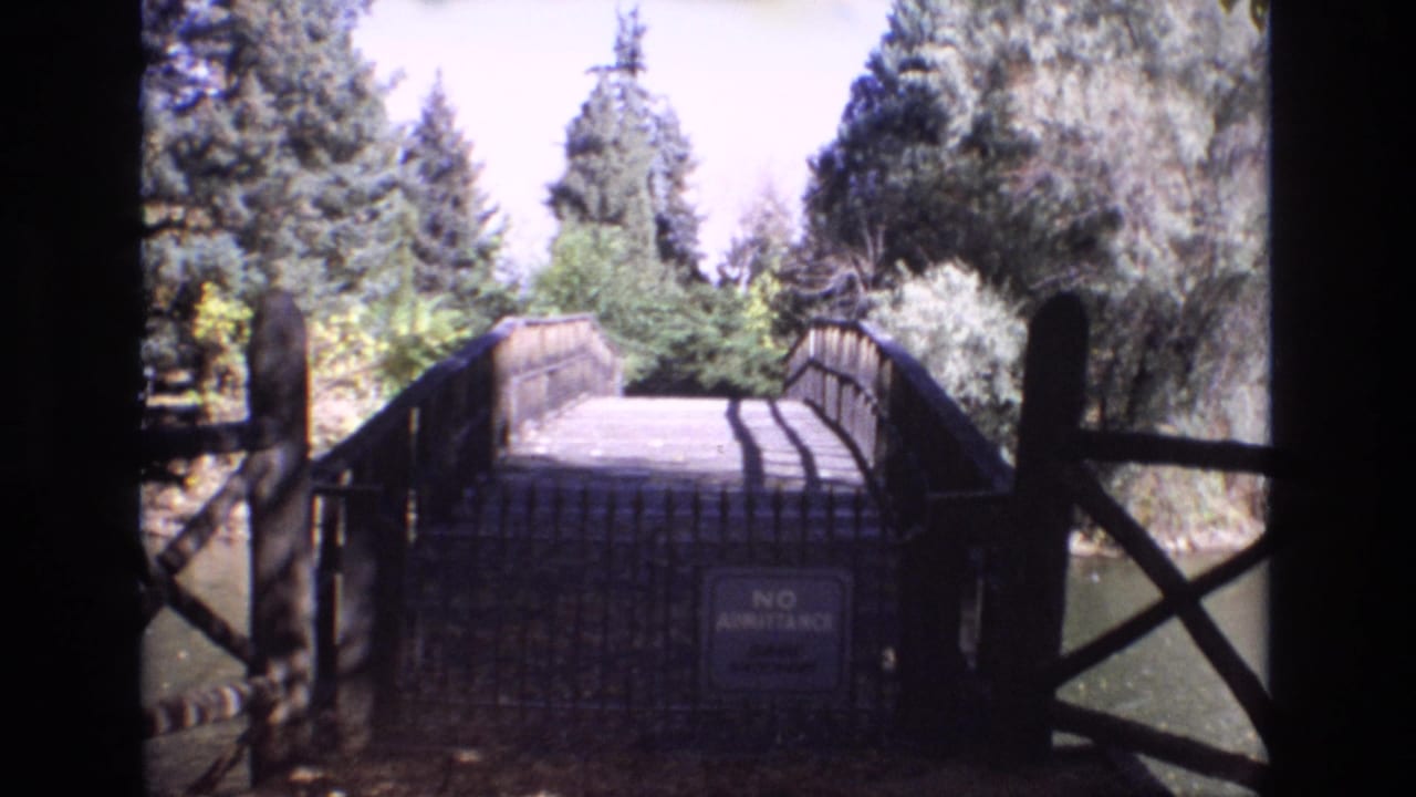 Wooden bridge over water with a no-admittance sign and dark railings in the foreground.