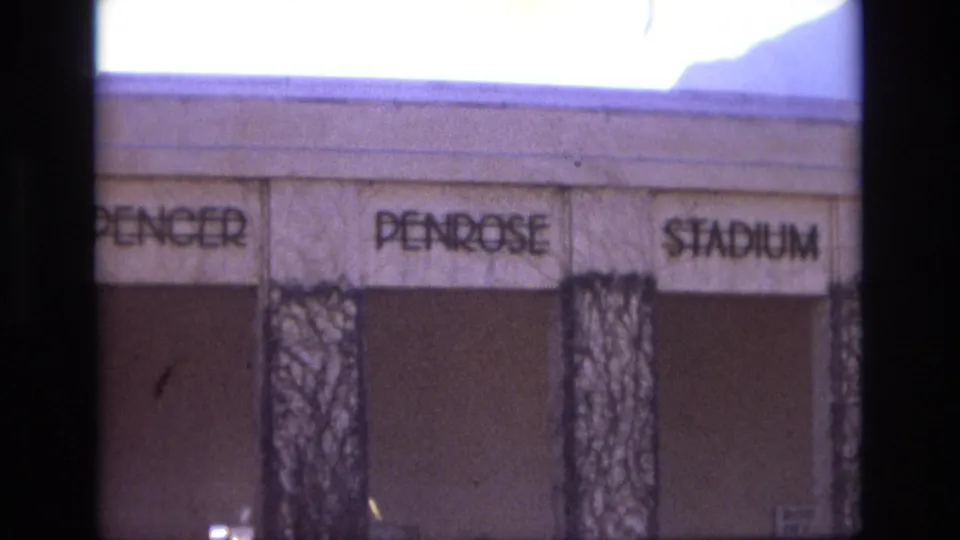 1974 Colorado Springs frame showing the Spencer Penrose Stadium facade with legible signage and bare vines on vertical supports.
