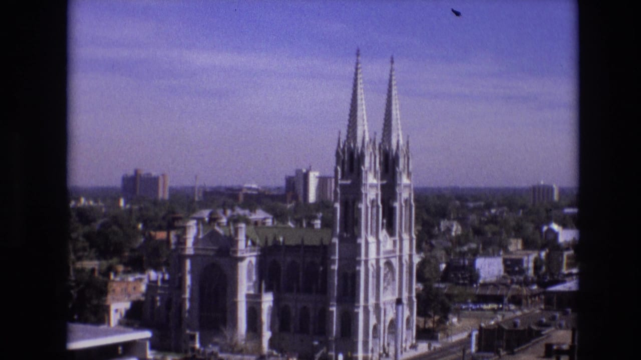 Denver, Colorado skyline view from 1974 showing twin church spires, nearby office buildings, trees, and a distant horizon.