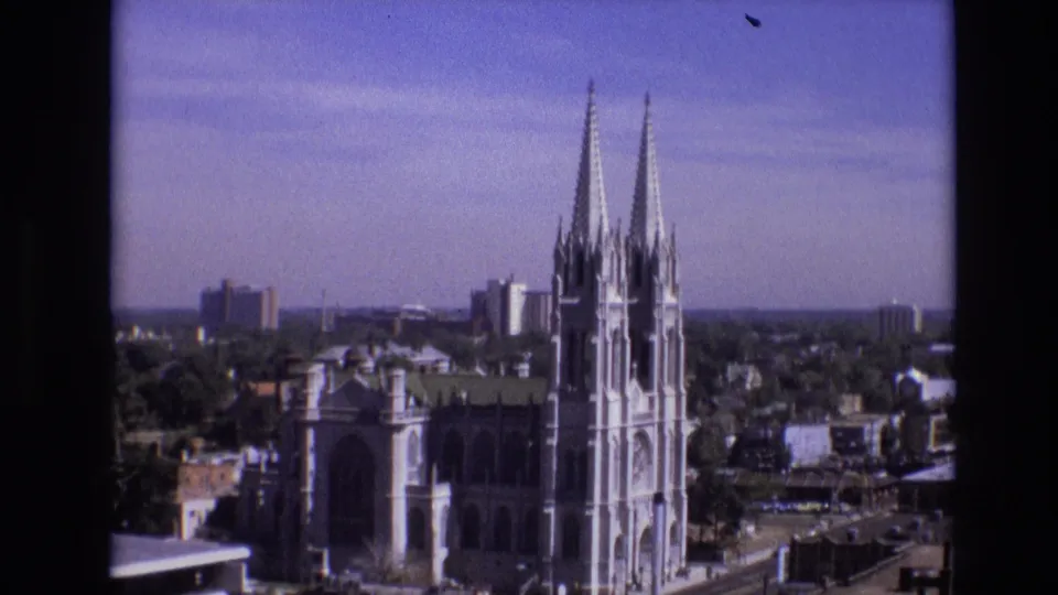 Denver, Colorado skyline view from 1974 showing twin church spires, nearby office buildings, trees, and a distant horizon.