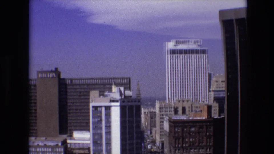 Denver skyline in 1974 with Security Life signage, high-rise office buildings, older downtown structures, and light clouds above the city.