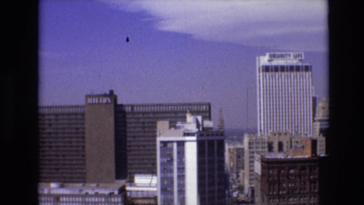 Downtown Denver skyline with Hilton and Security Life towers under a blue sky.