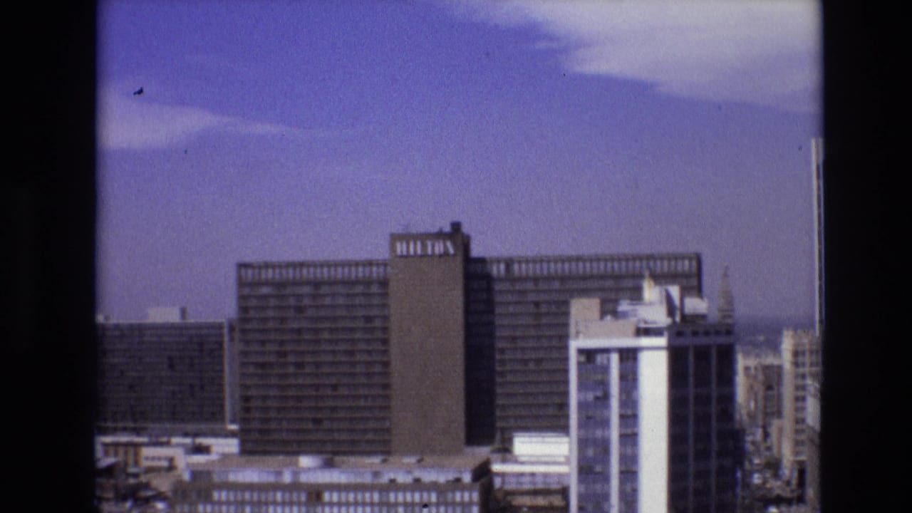 Hilton hotel tower and nearby downtown buildings against a blue sky.