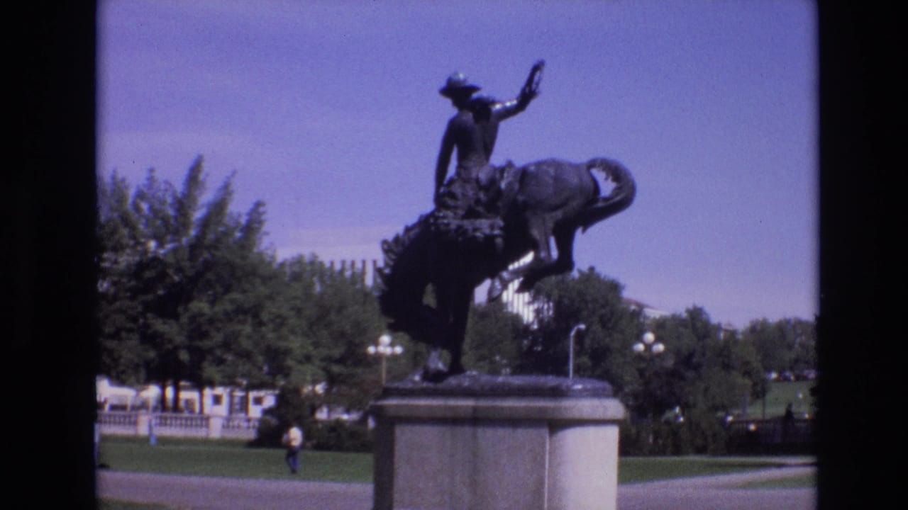 Rider and horse statue framed against trees and open sky.