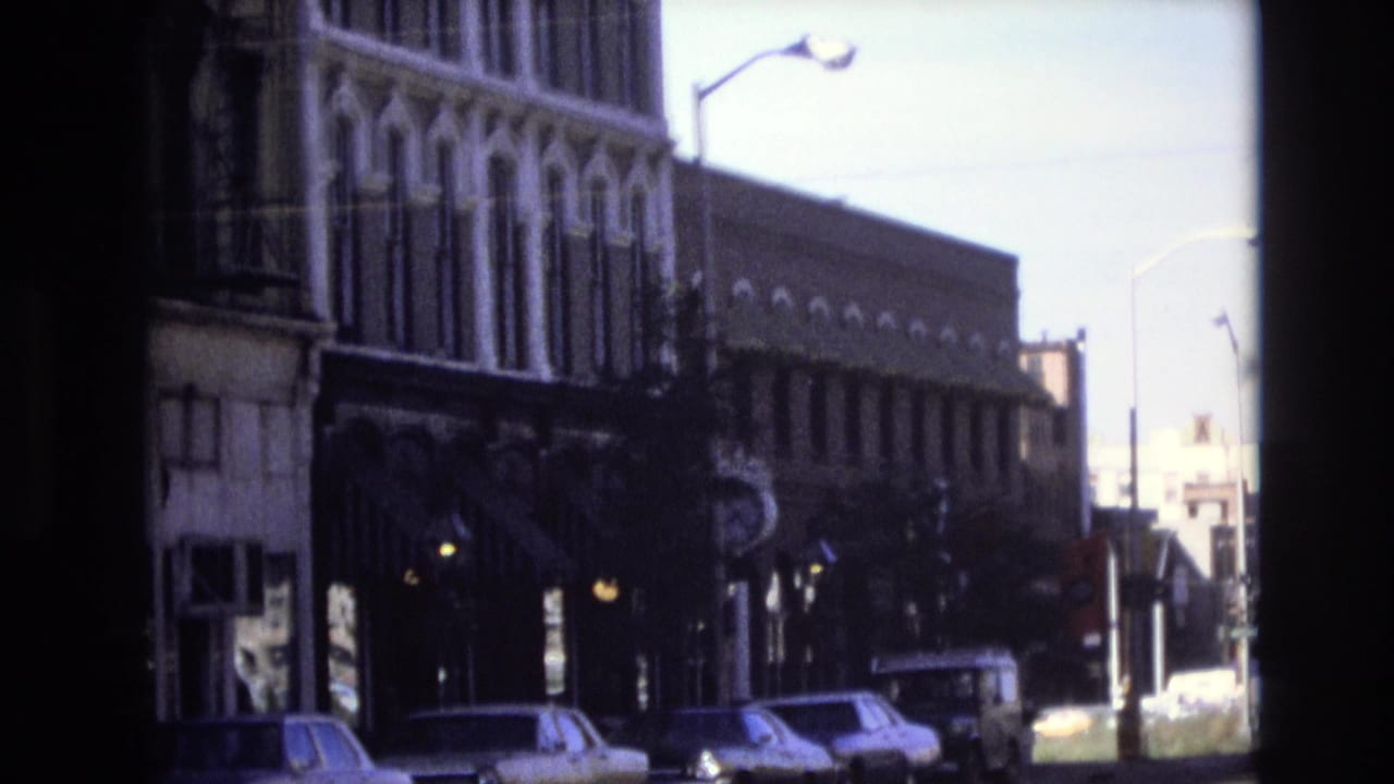 A similar street view shows parked cars, storefronts, and a bright intersection beyond.