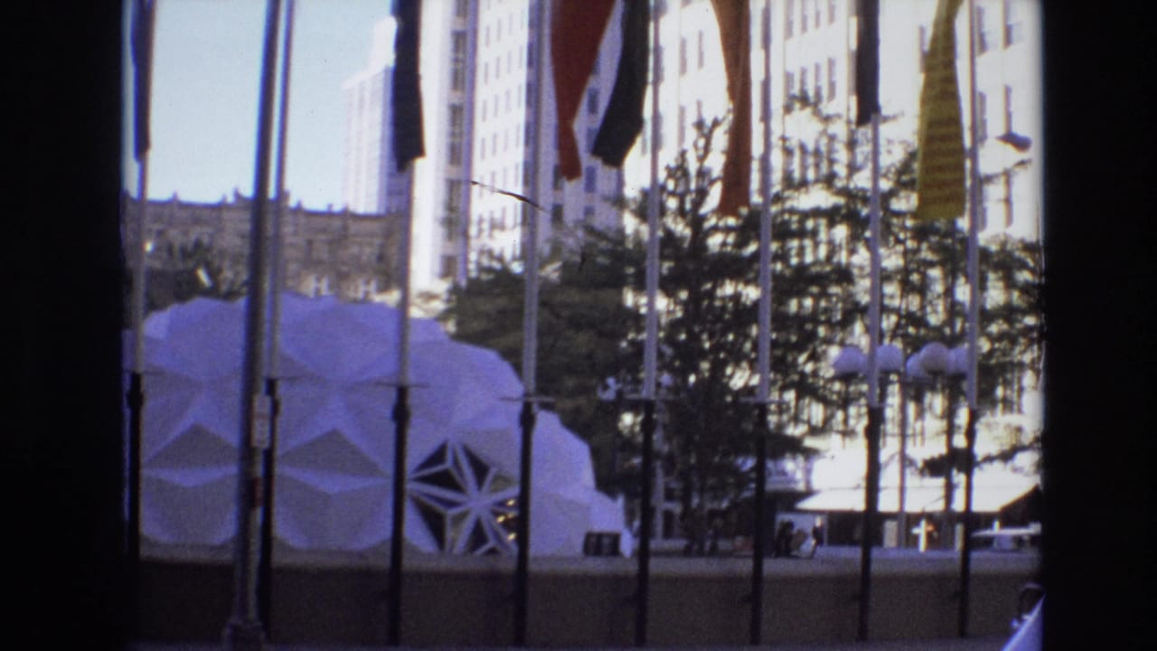 Downtown street view with a geometric dome structure, mirrored windows, streetlamps, and tall buildings.