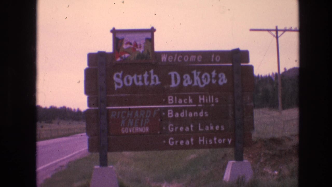 Wooden South Dakota welcome sign beside a rural highway.