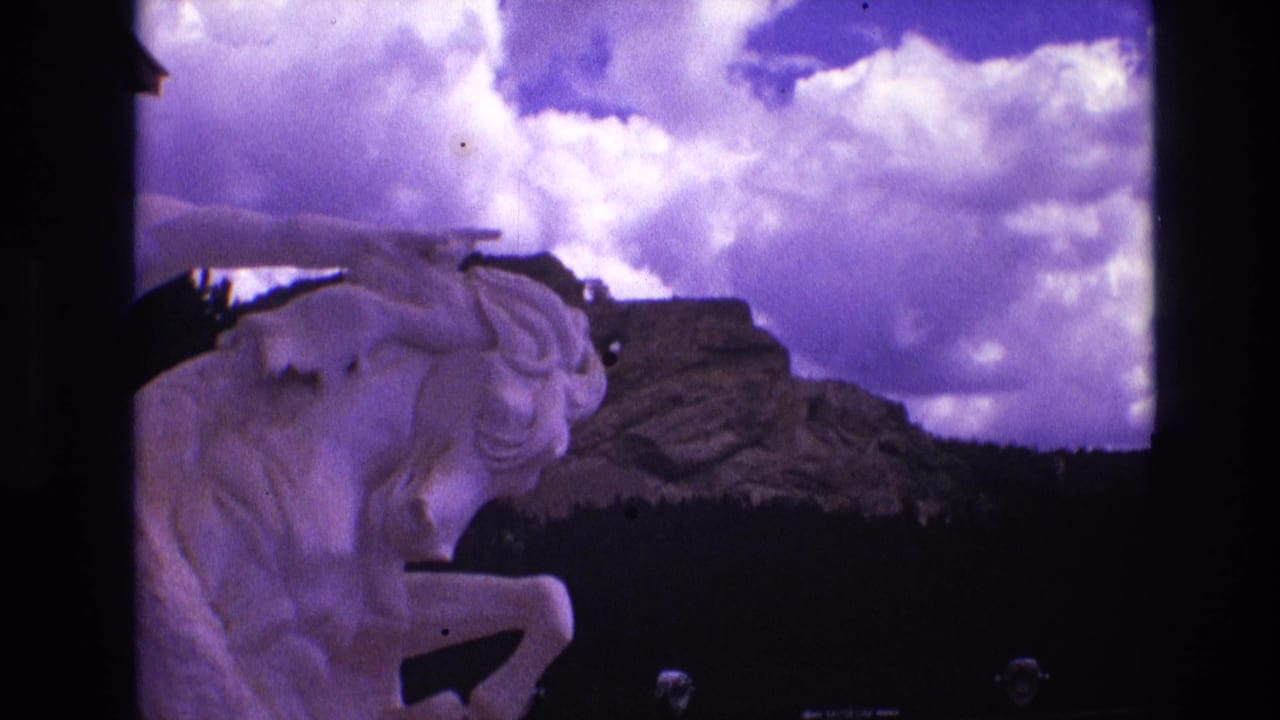 White horse statue at left with rocky hills, trees, and bright clouds behind it.