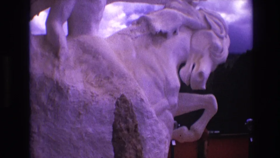Final 1974 South Dakota frame showing the white rearing horse sculpture glowing purple, with the dark mounted object and red lower display panels still visible.