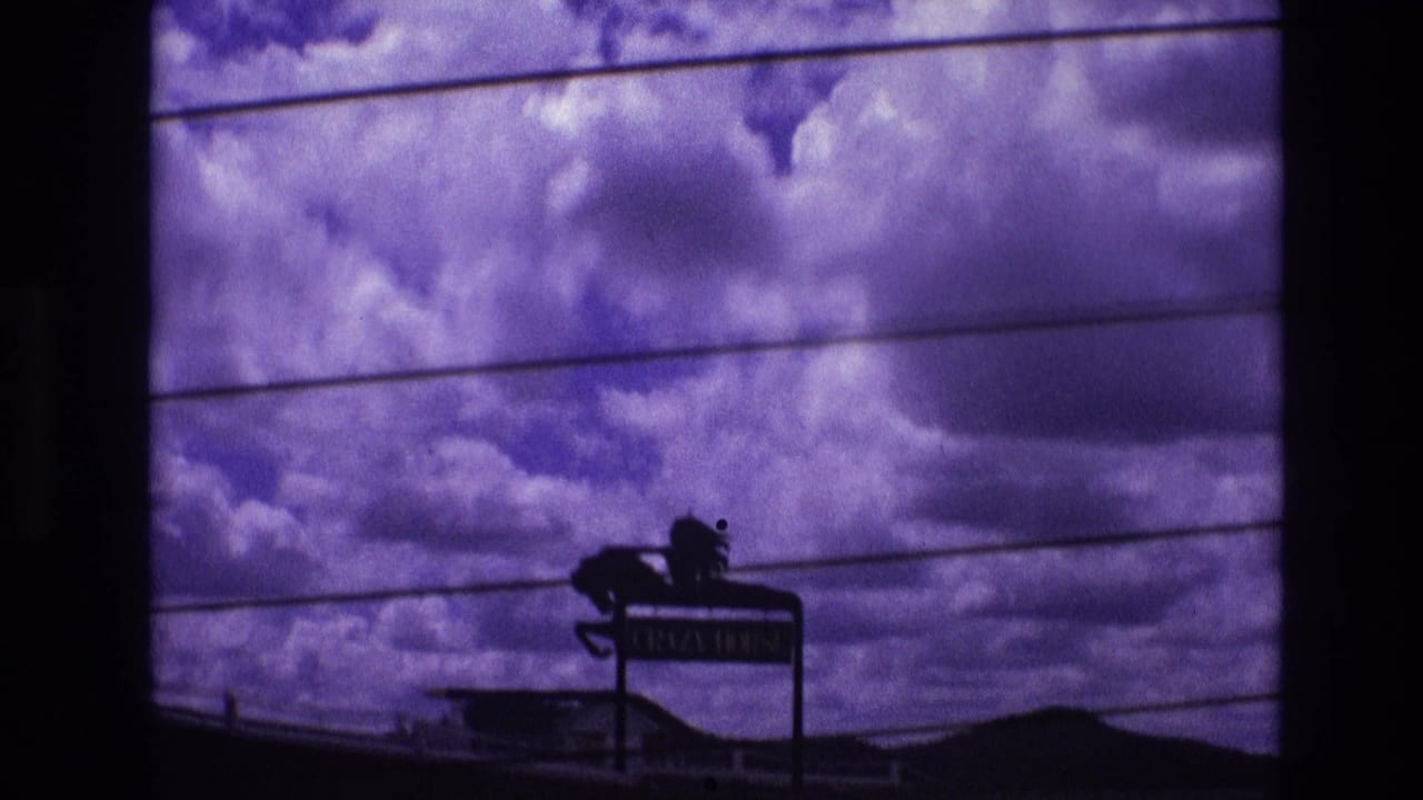 1974 South Dakota 8mm travel footage shows dramatic purple-tinted clouds through a vehicle-window view, with power lines and a dark roadside sign silhouette below.
