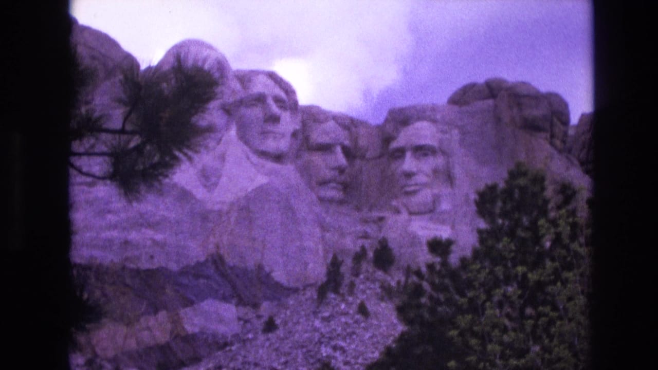 Mount Rushmore presidential carvings with trees and rocky foreground.