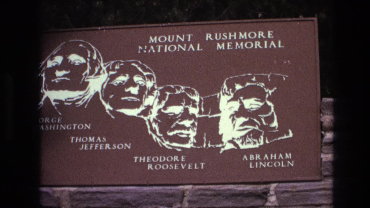 Brown Mount Rushmore sign with white presidential silhouettes and engraved names.