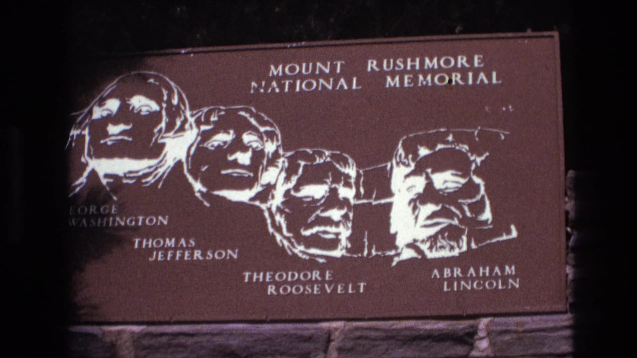 Brown Mount Rushmore sign showing four presidential heads and white lettering.