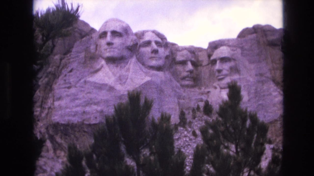 Mount Rushmore presidential carvings framed by dark pine branches and cloudy sky.