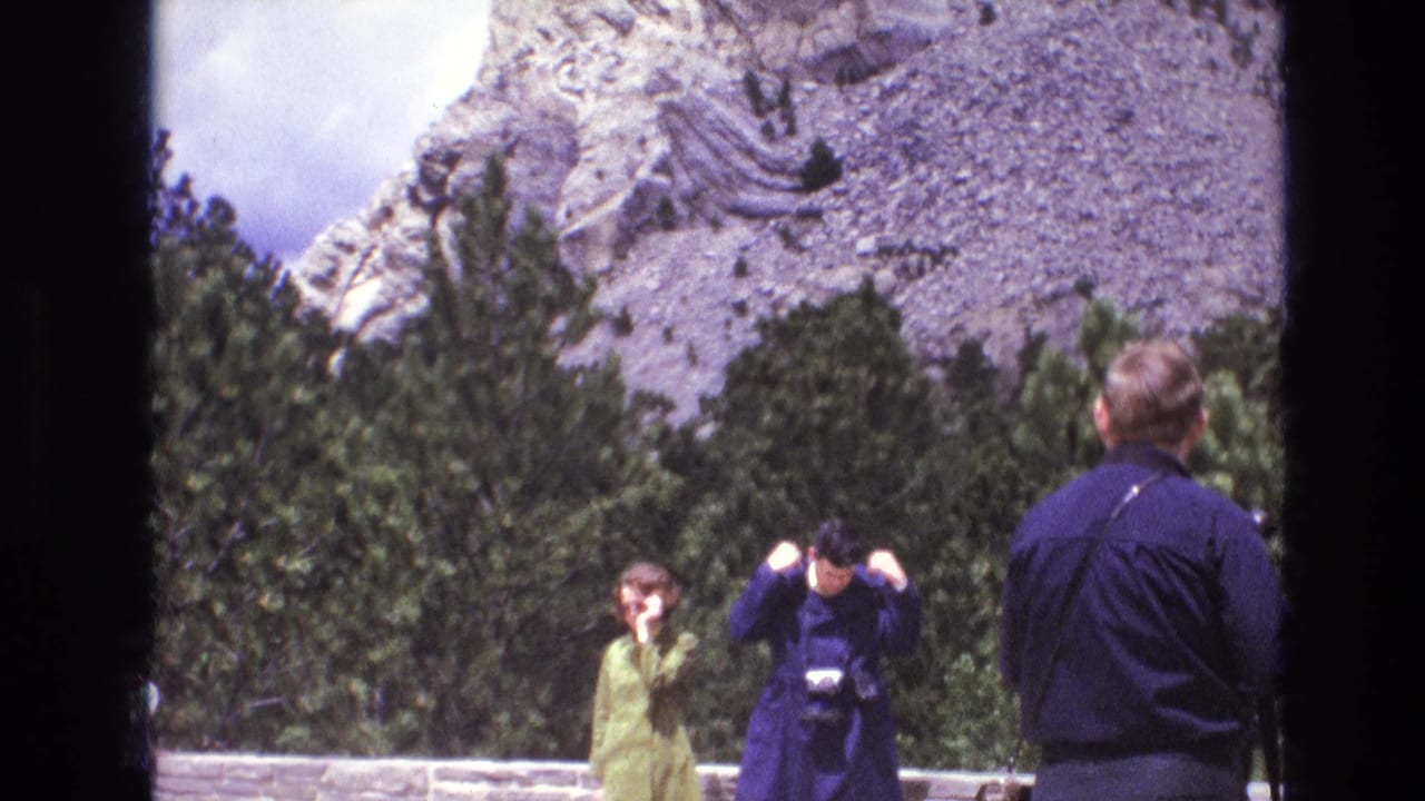 Visitors stand by a low wall as one person raises a camera.
