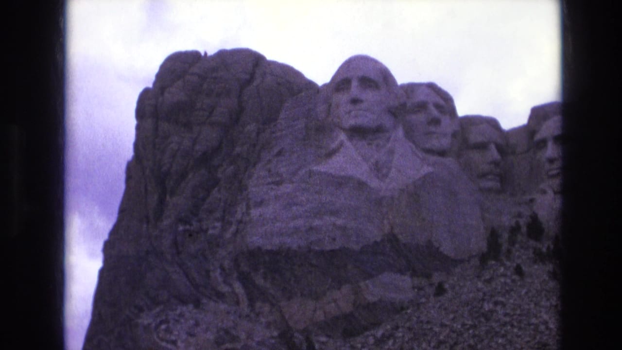 1974 8mm view of Mount Rushmore National Memorial in South Dakota, with Washington centered and other presidential carvings partly visible.