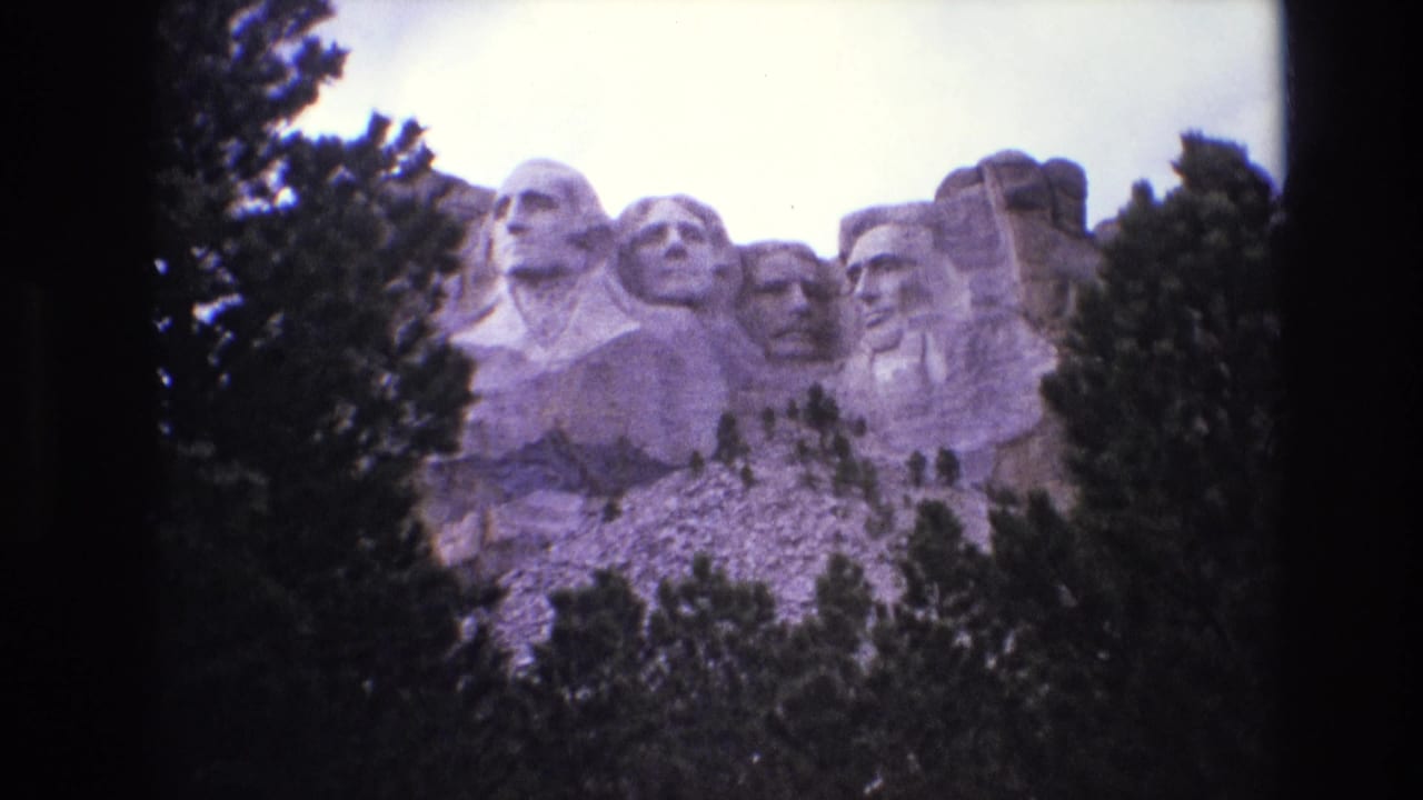 Carved presidential heads at Mount Rushmore framed by trees and sky.