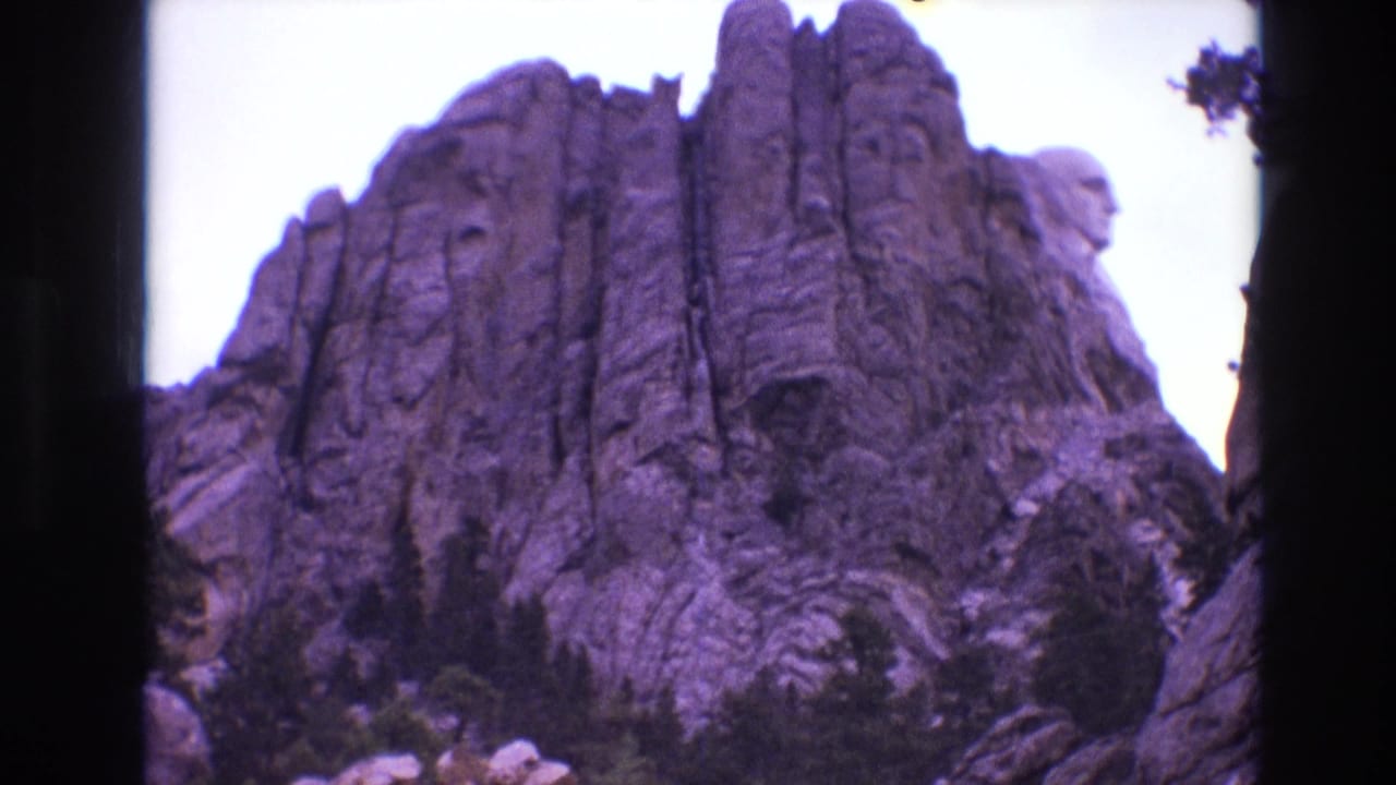 Granite monument face and cliff formations above dark trees.