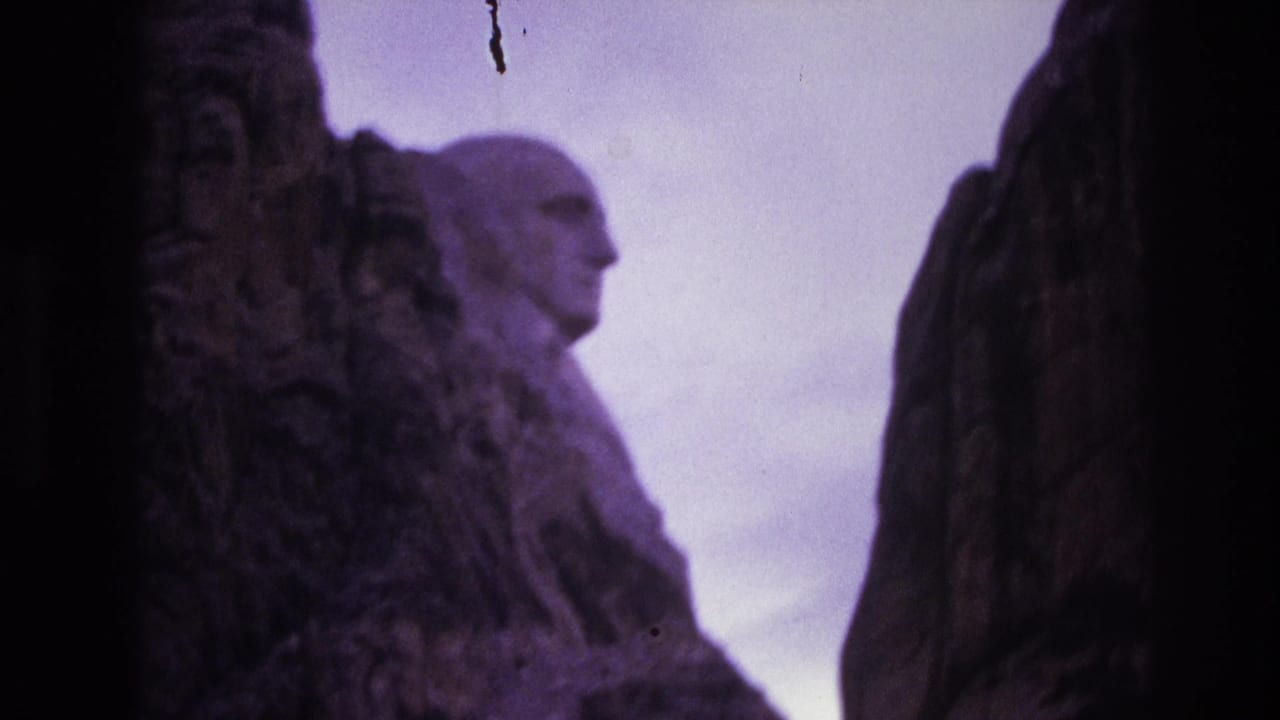 Carved presidential profile at Mount Rushmore seen beyond shadowed rock.