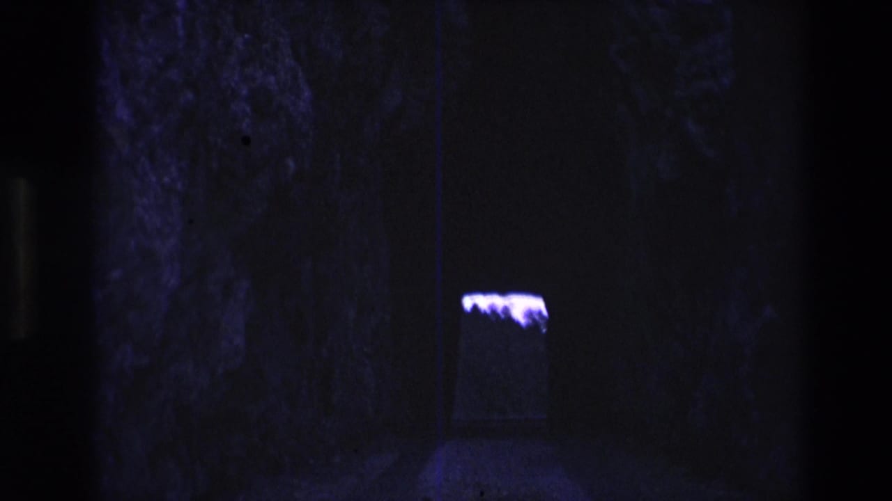 Dark stone interior with a purple glow near the right side of the frame.