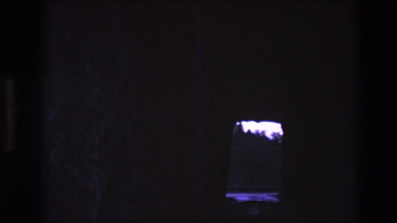 Dark interior with a small glowing rectangular tank at the right side of the frame.