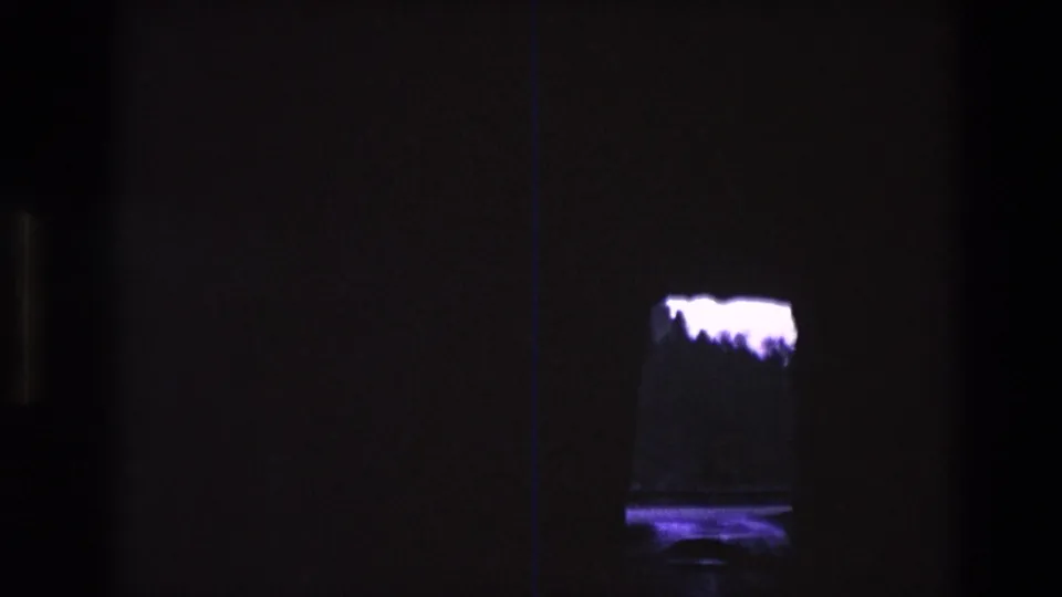 1974 South Dakota 8mm frame showing the small tank or display more centrally, with a bright irregular white mass and purple-blue reflection below it.
