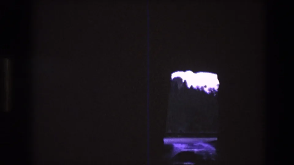 1974 South Dakota 8mm frame showing a small illuminated tank or display in darkness, with the white floating-looking form filling more of the visible opening.