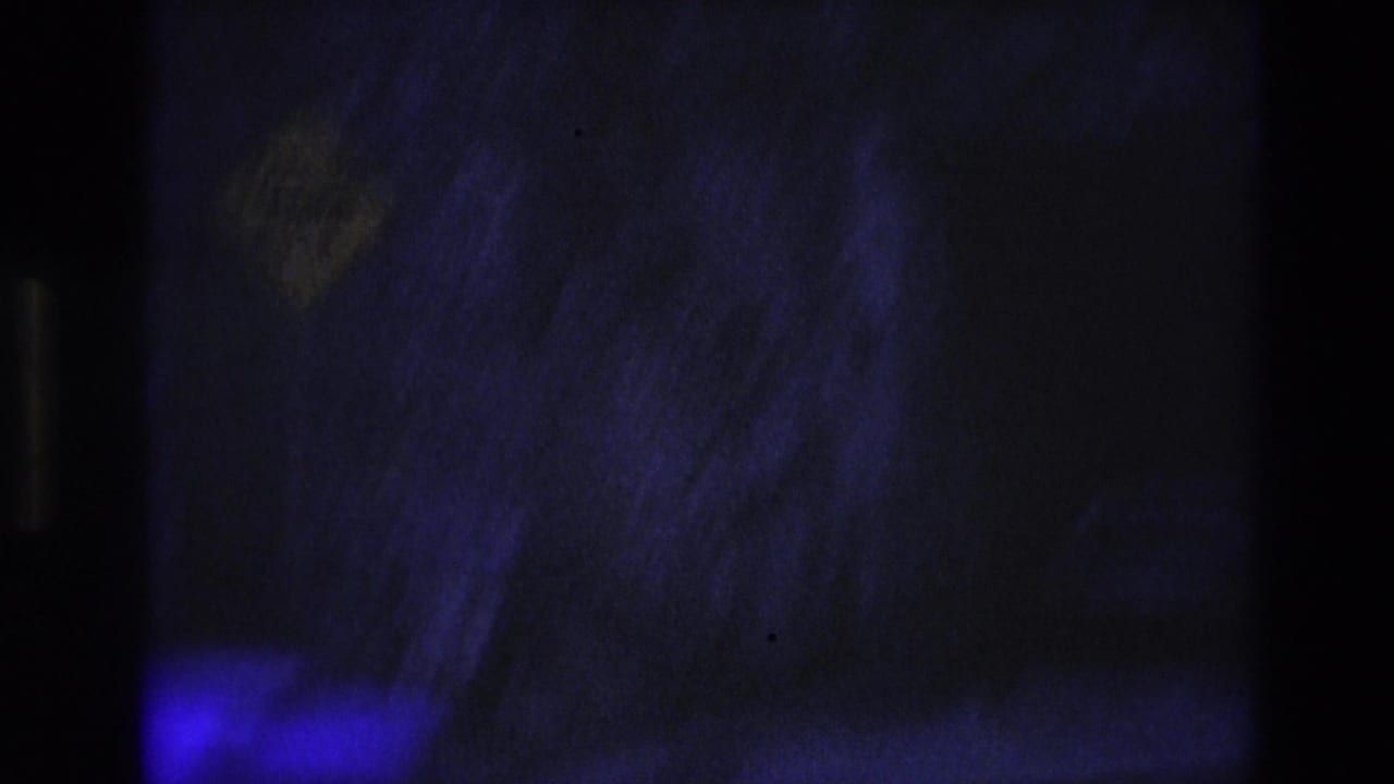 Low-light 1974 South Dakota frame with rough rock surfaces, deep blue-purple color, and a mostly shadowed passageway area.