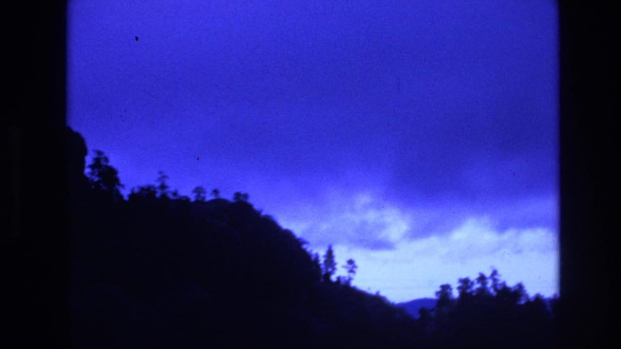Tree-covered ridge silhouetted against a blue cloudy sky.