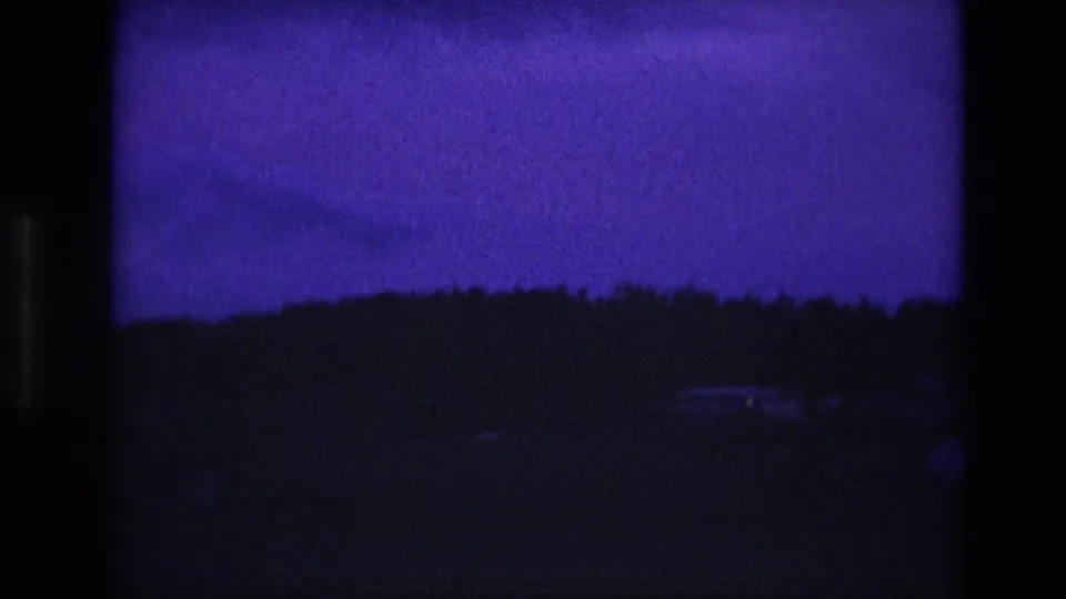 South Dakota 1974 8mm frame with a nearly black treeline and distant horizon under a deep blue-purple dusk sky.