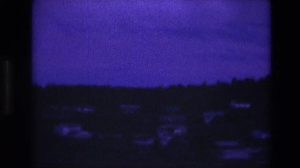 South Dakota 1974 8mm frame with a dark rolling horizon, indistinct pale points near the lower edge, and a grainy purple dusk sky.
