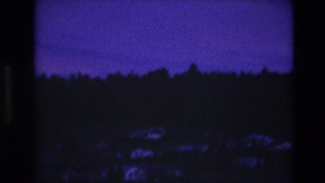1974 South Dakota 8mm frame showing a deep purple night sky over a dark treeline and faint low landscape shapes.
