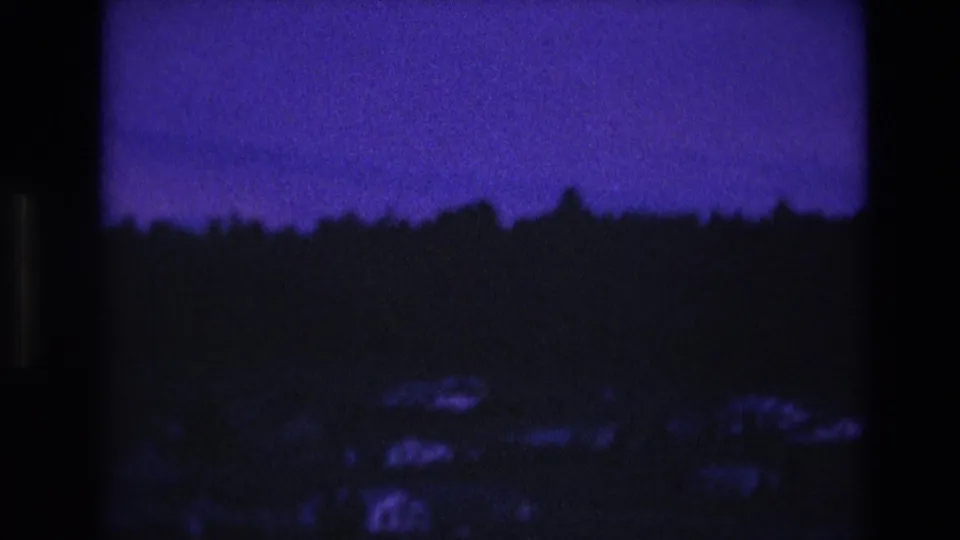 1974 South Dakota 8mm frame showing a deep purple night sky over a dark treeline and faint low landscape shapes.