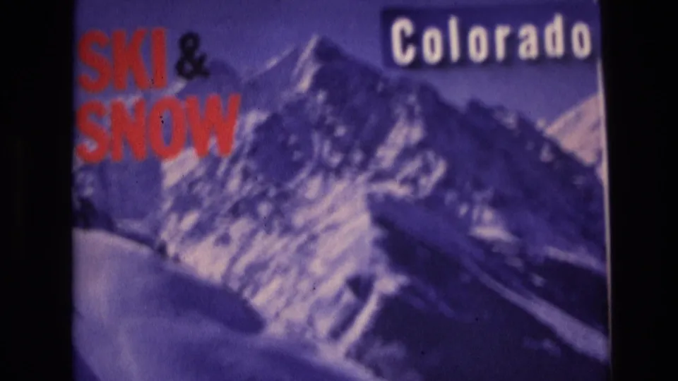 1974 Vail, Colorado 8mm frame showing a slightly blurred ski advertisement with red SKI & SNOW lettering over a purple mountain scene.