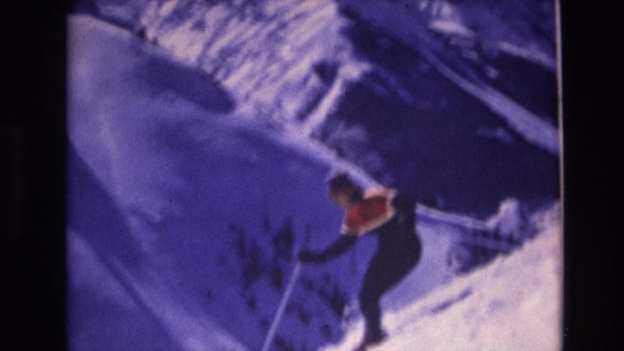 Skier in a dark outfit and red top descending a snowy slope.