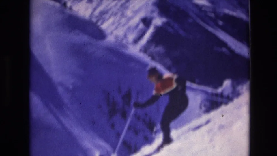 The skier continues downhill across the snowy Vail slope, with poles angled into the snow and the frame showing heavy 8mm grain and color shift.