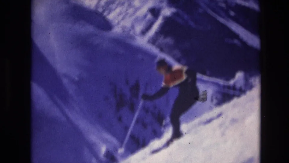 A home-movie frame shows the skier leaning into the descent on a snowy Vail hillside, with soft focus and visible film grain.