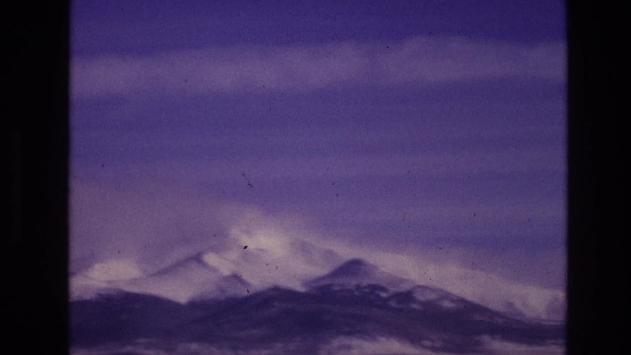 Distant snowy peaks and dark ridgeline under a purple sky.