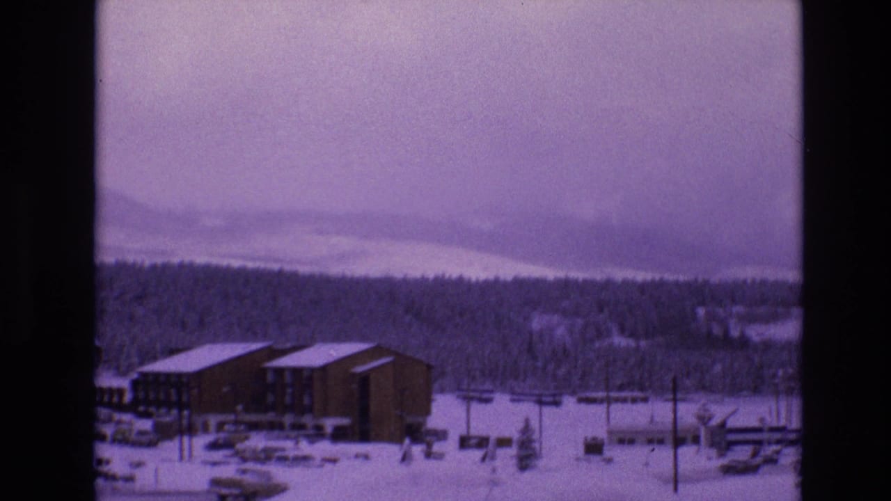 A 1974 Vail, Colorado winter view shows snow-covered resort buildings, parked cars, utility poles, and forested mountain slopes under a purple-blue 8mm color cast.