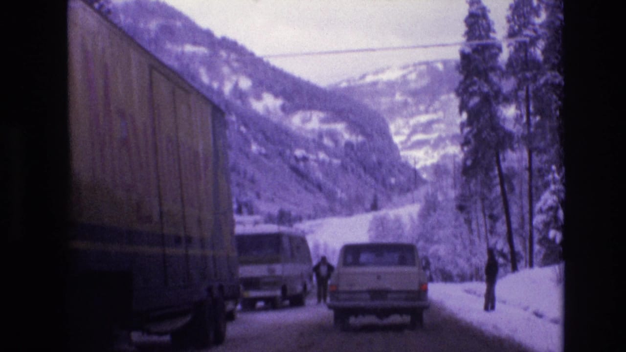 Large truck passes a white van and station wagon on a snowy road.