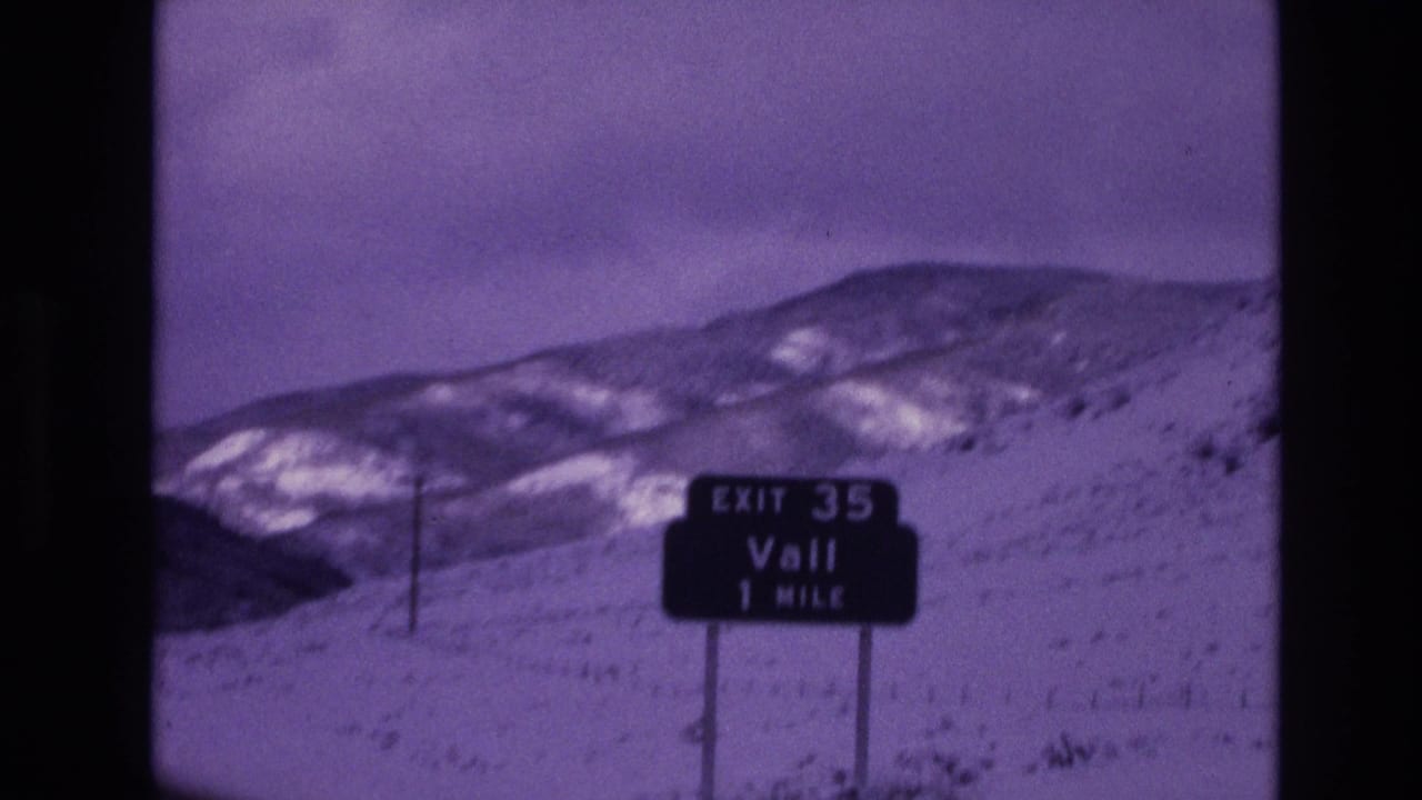 1974 8mm frame of an Exit 35 Vail 1 Mile highway sign beside a snow-covered mountain slope in Colorado.