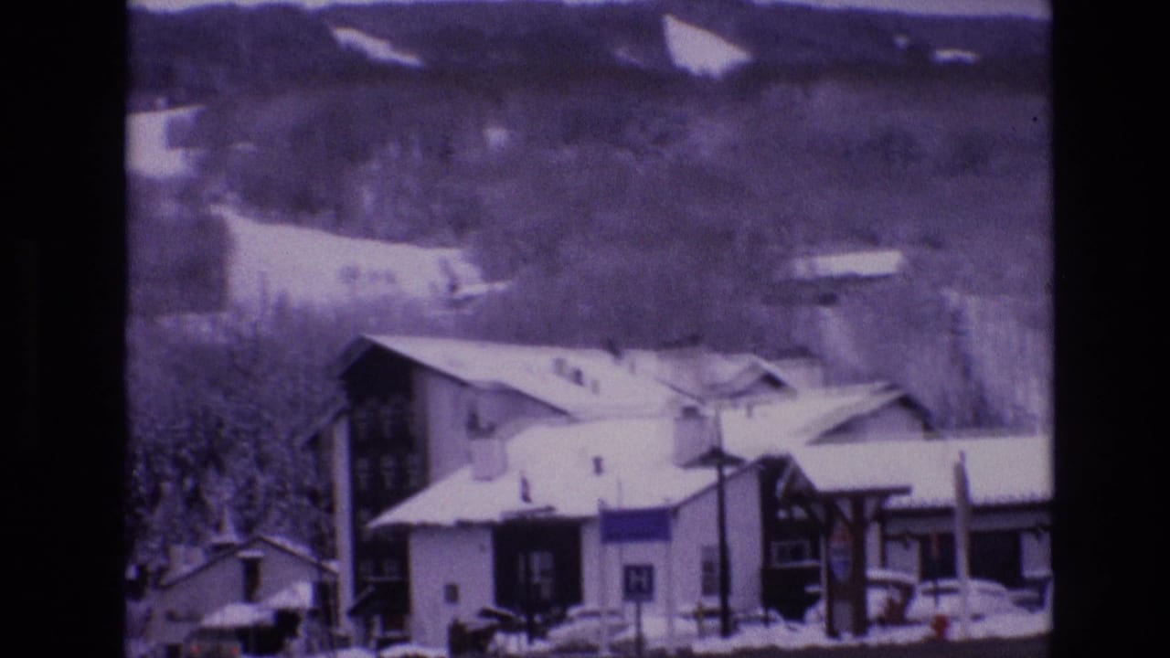 Snowy Vail, Colorado buildings and roadside structures appear below tree-covered mountain slopes in this 1974 home-movie frame.