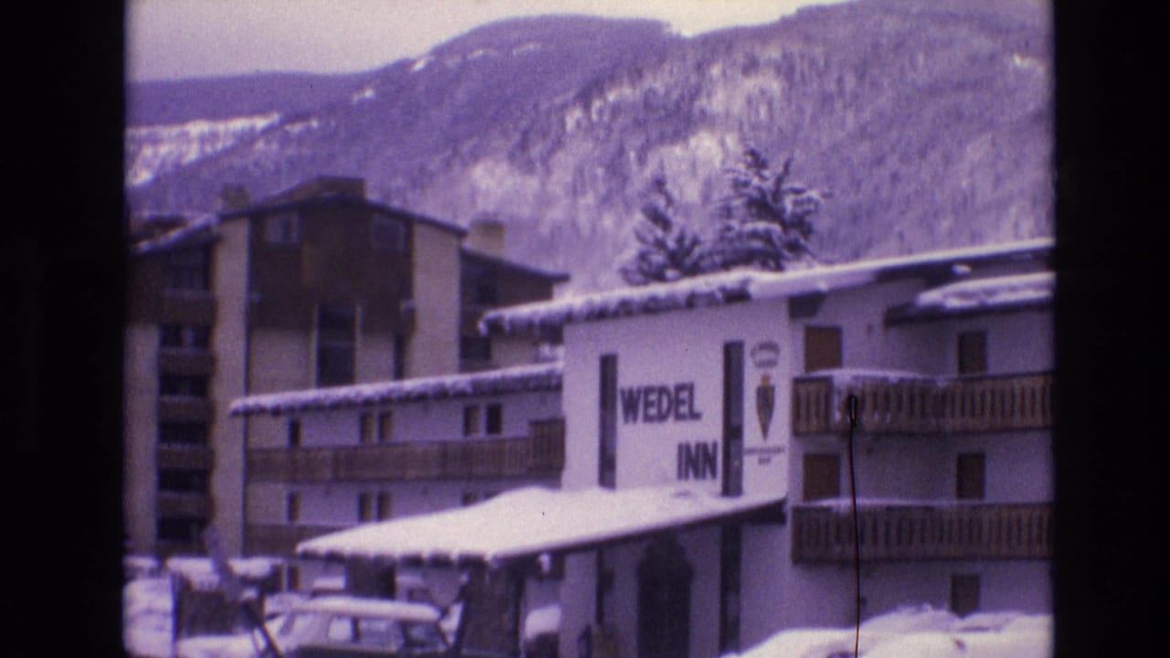 1974 Vail, Colorado home-movie frame showing the Wedel Inn sign on a snowy lodge building, parked cars, snowbanks, trees, and mountains in the background.