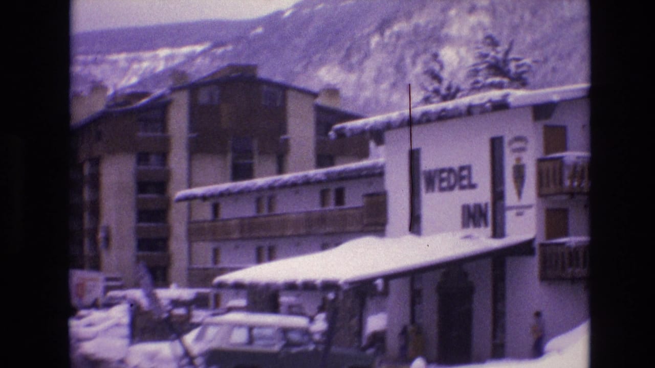 1974 Vail, Colorado frame with the Wedel Inn facade at right, snow-covered roofs, parked cars, and layered mountain slopes behind the resort buildings.