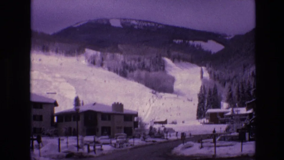 1974 Vail, Colorado home-movie frame showing snow-covered lodge buildings and ski runs at the base of Vail Mountain.