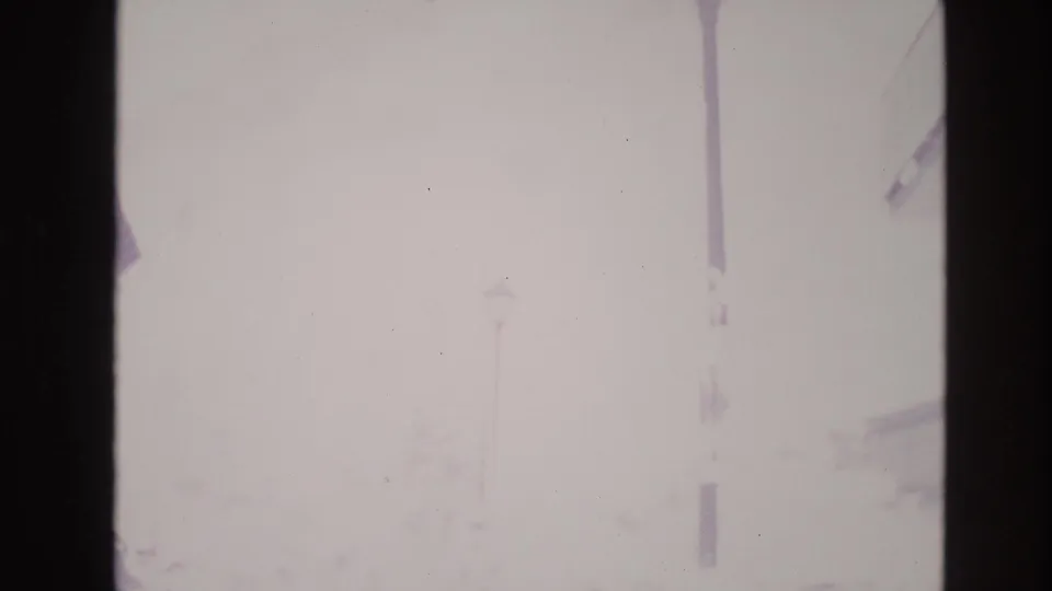 Final 1974 Vail frame shows the resort street almost completely obscured by snow glare, leaving a faint lamp pole and building edge visible.